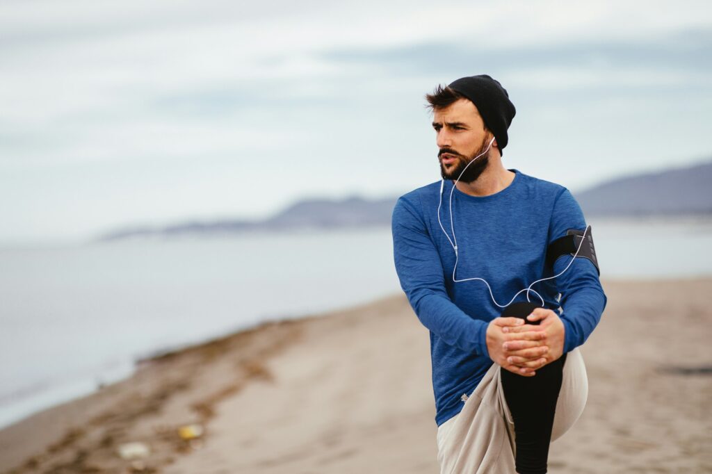 Young athletic man stretch out on the beach