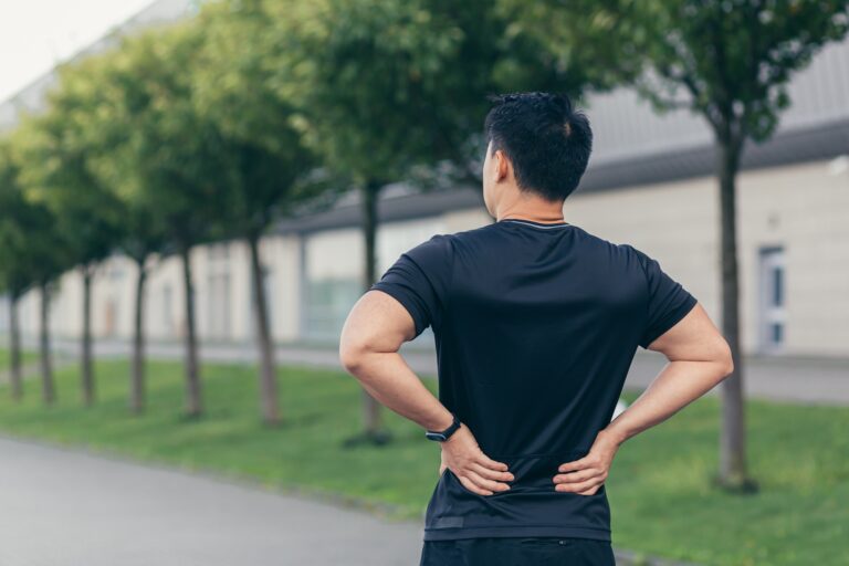 Asian man holding back pain after running and fitness